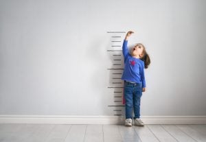 Child measuring height against a wall with growth marks as a sign of growth and opportunity