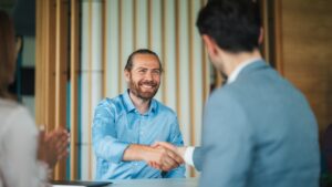 Man shaking hands with someone symbolizing How to Sell Shares of a Private Company Finding a Buyer